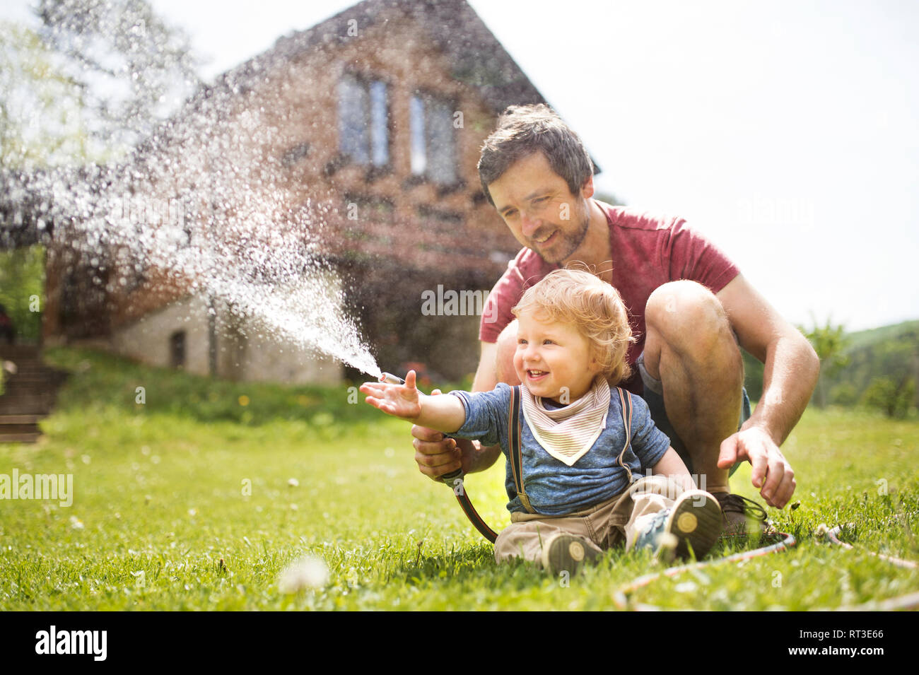 Little boy with his father watering the lawn Stock Photo