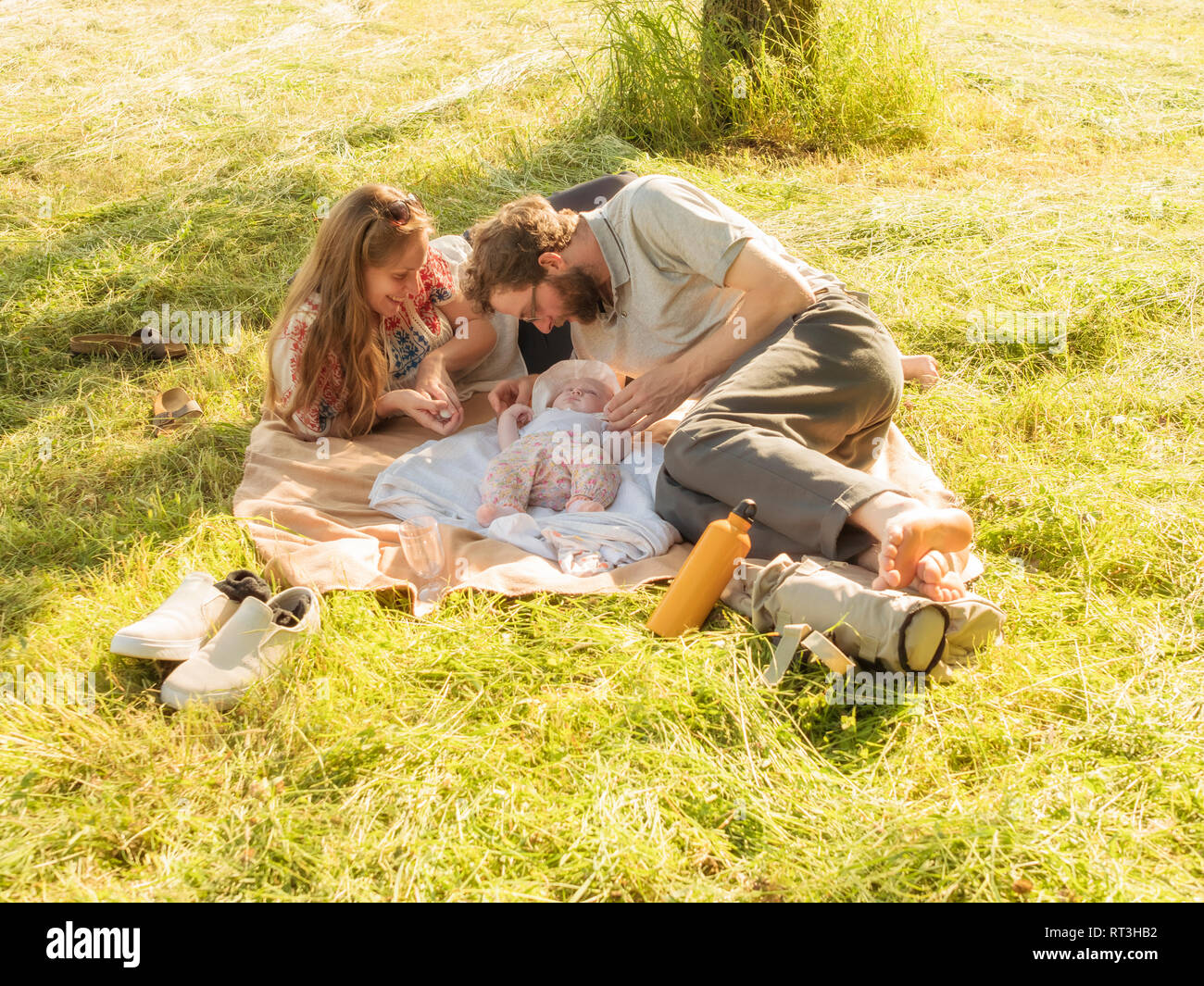 Young couple relaxing with baby girl on blankets on a meadow Stock Photo