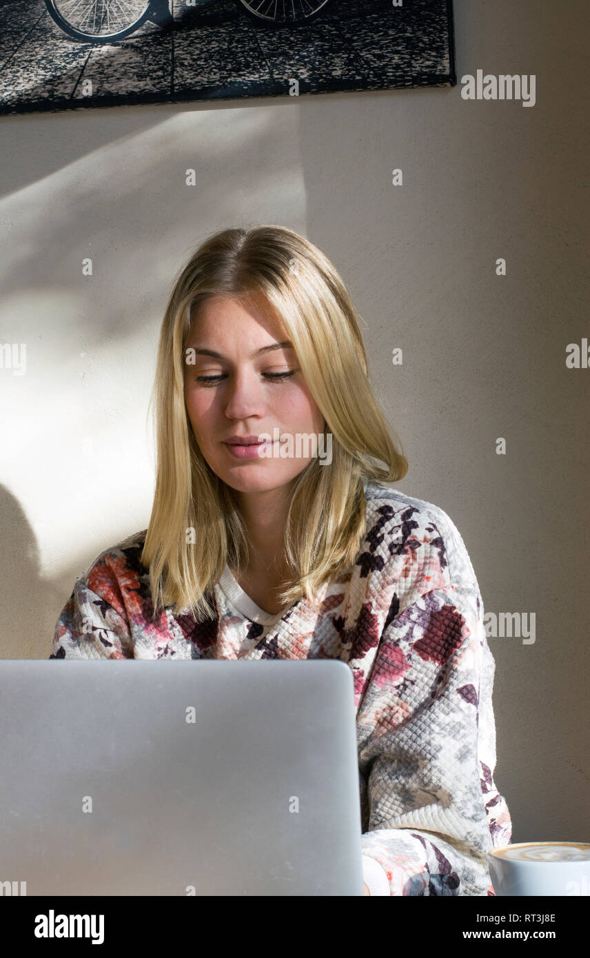 Portrait of blond woman working on  laptop in a cafe Stock Photo