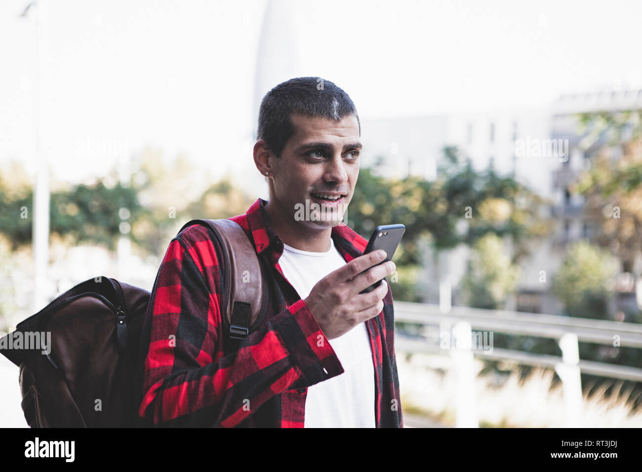 Young man with backpack and cell phone on the go Stock Photo