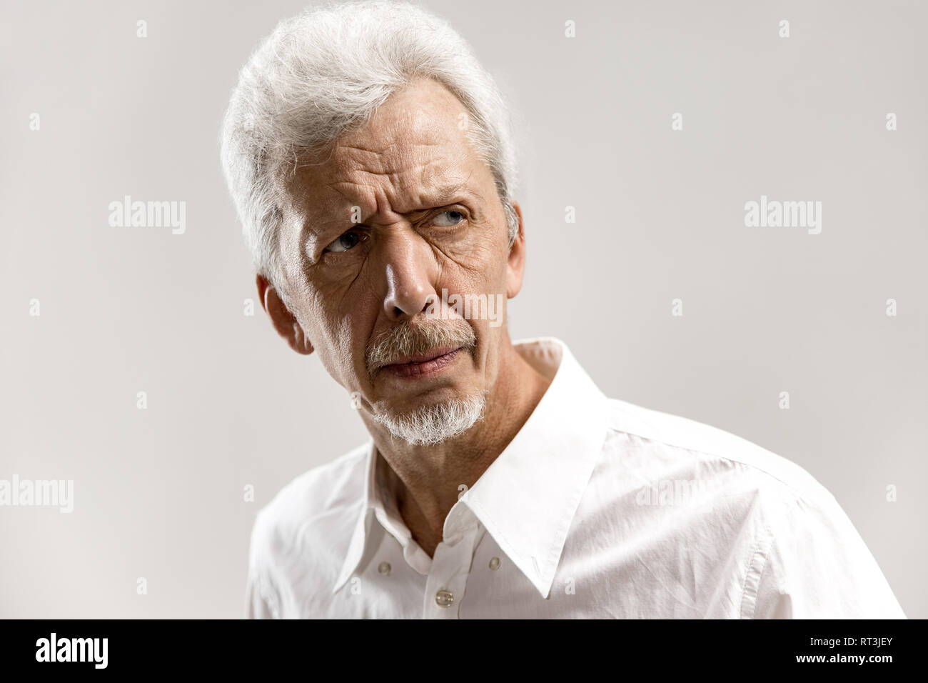 Serious businessman standing, looking at camera isolated on gray studio ...