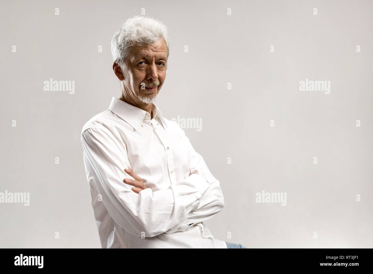 Serious businessman standing, looking at camera isolated on gray studio ...