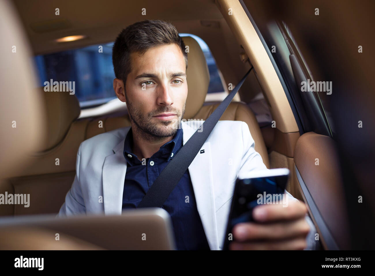Young businessman sitting in car, using smartphone Stock Photo