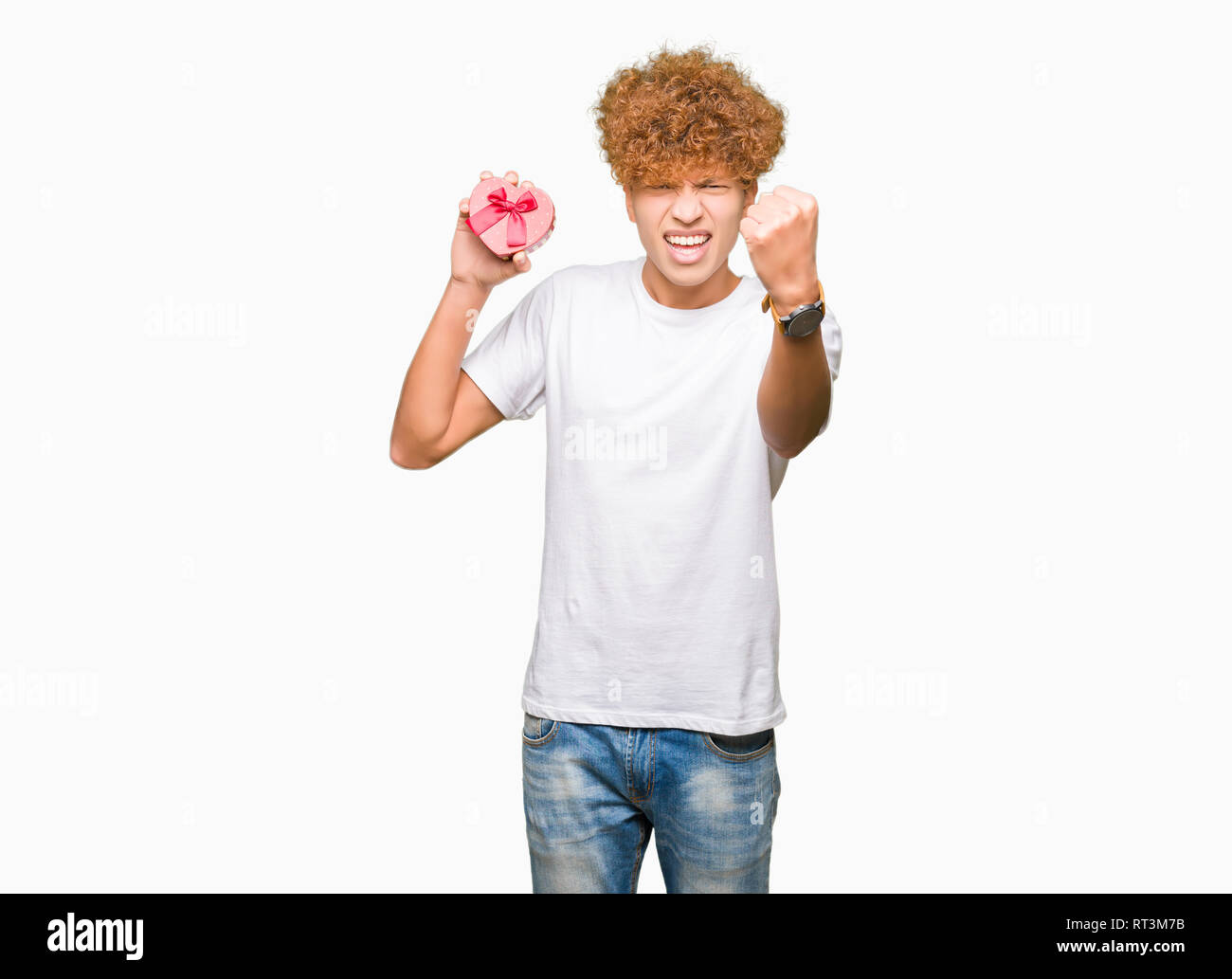 Man Raging Out Gift Young handsome man holding heart box as gift of valentine's day annoyed ...