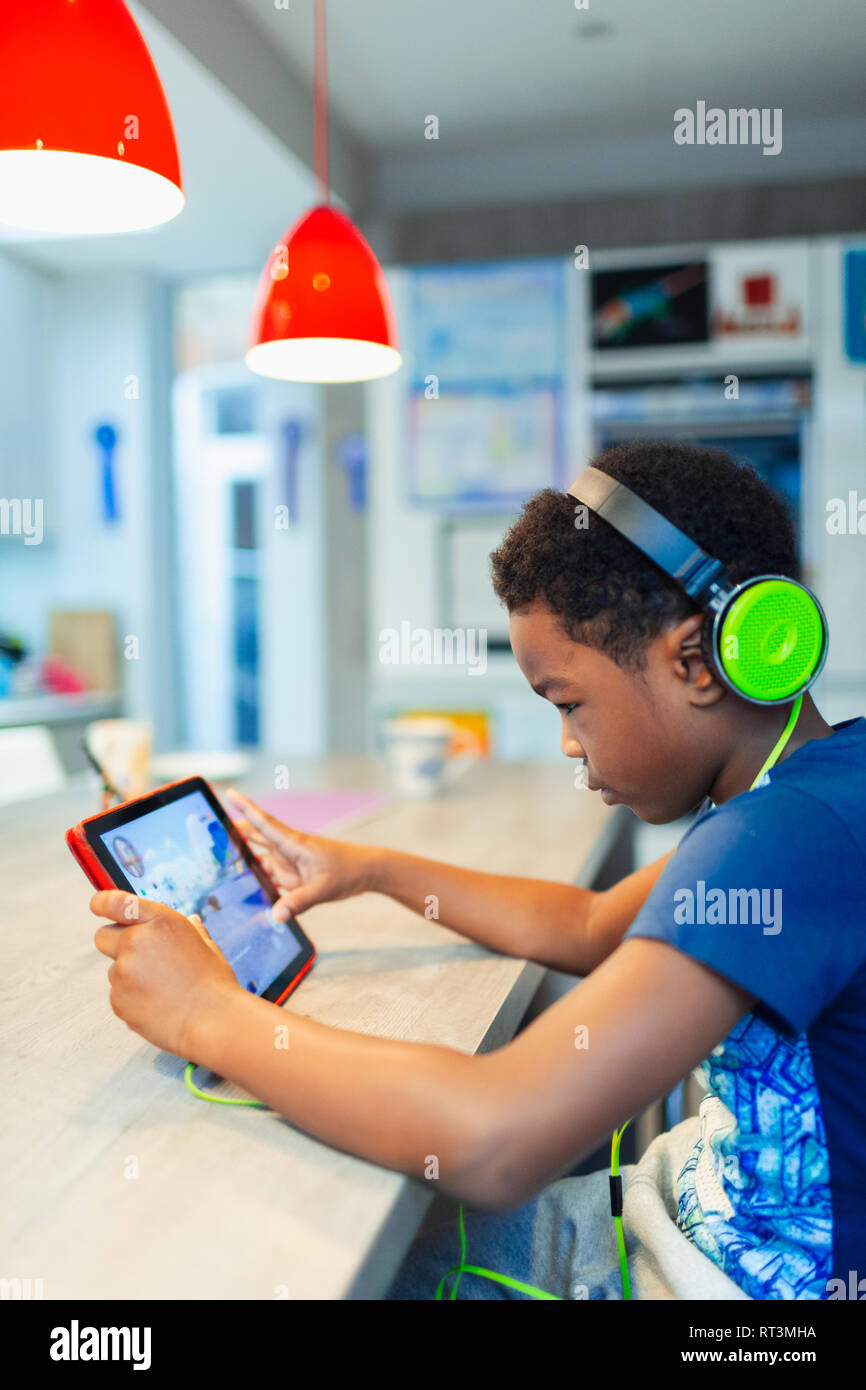 Boy with headphones and digital tablet playing video game Stock Photo
