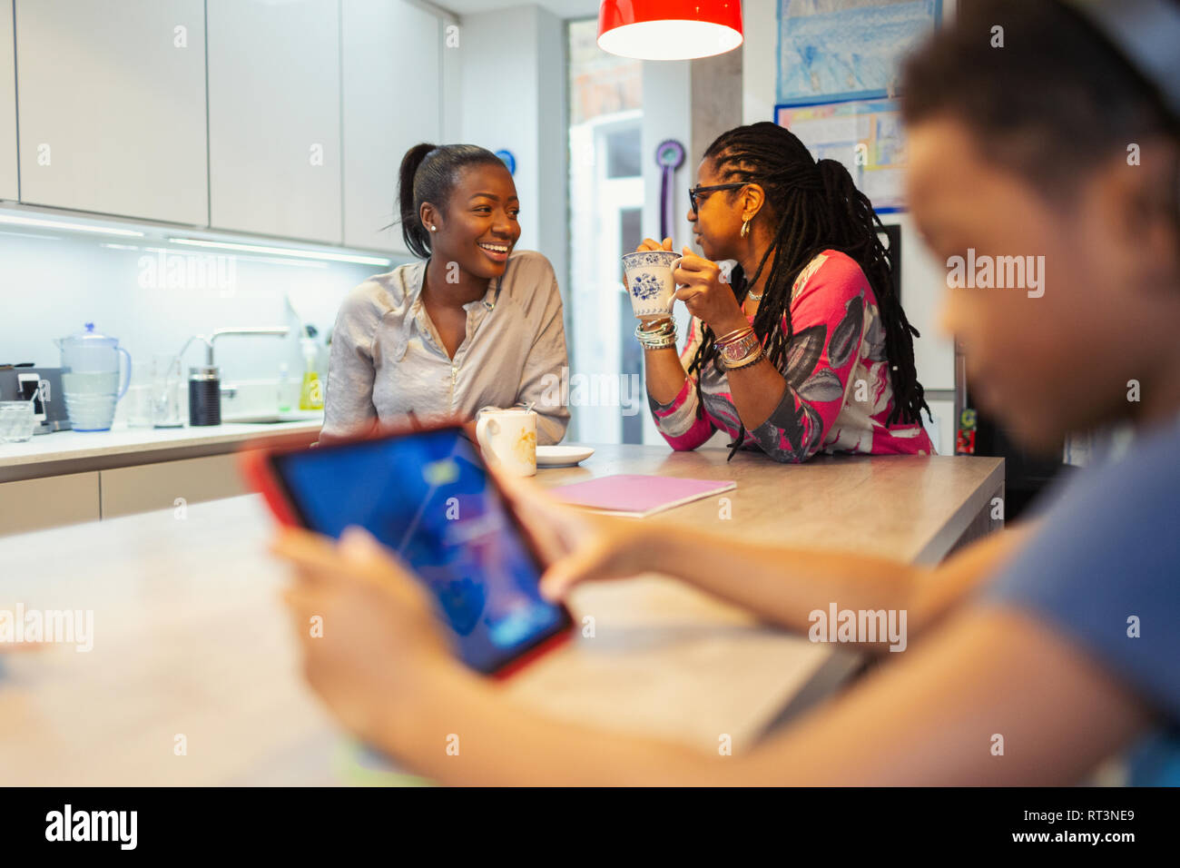 Mother and adult daughter talking in kitchen Stock Photo