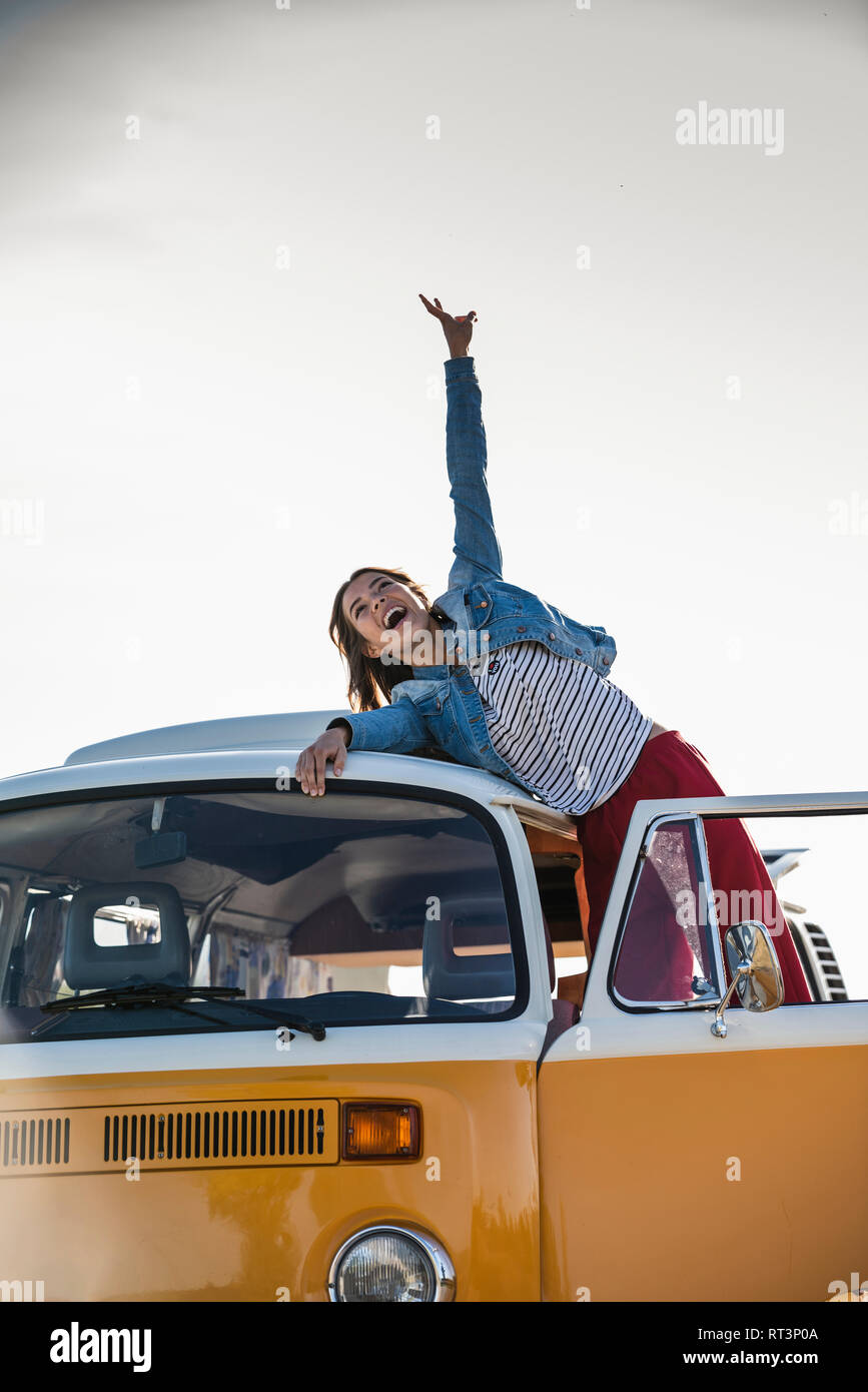 Pretty woman on a road trip with her camper, cheering, enjoying freedom ...