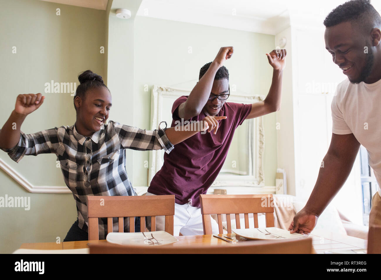Playful teenage brother and sister dancing in dining room Stock Photo