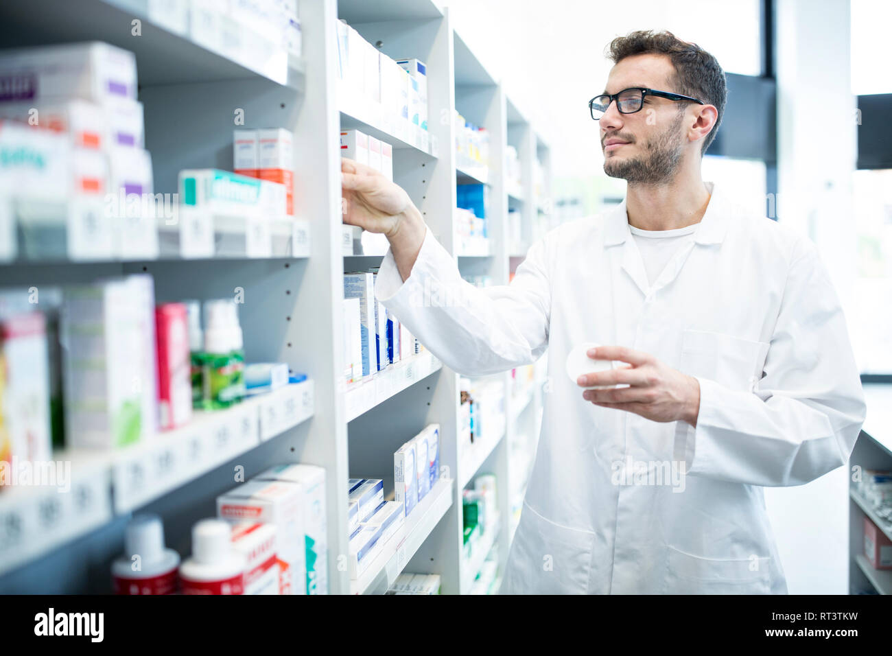 Pharmacist taking medicine from shelf in pharmacy Stock Photo