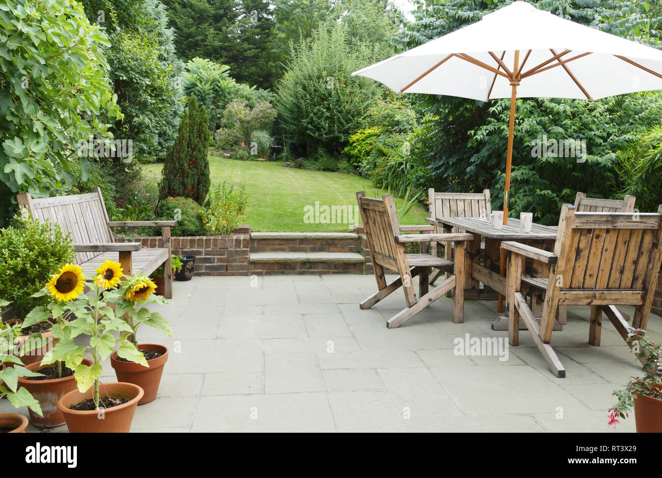 London garden in summer with patio, wooden garden furniture and a parasol or sun umbrella Stock Photo