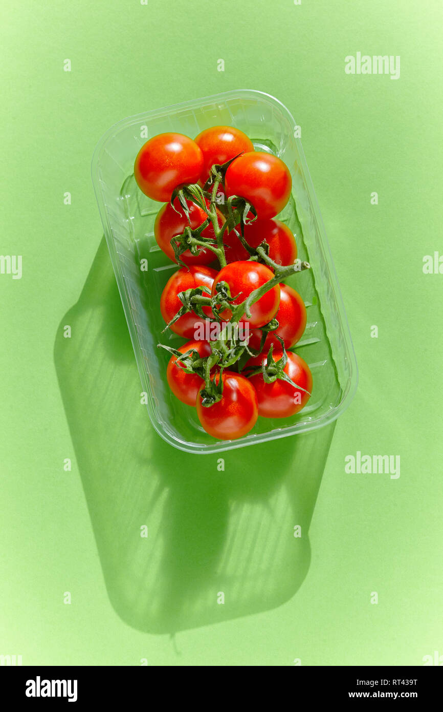 Red tomatoes in an industrial tray on a green background. From the view from above Stock Photo