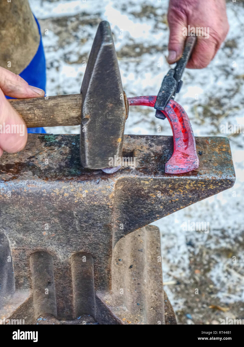 Blacksmith hot horseshoe. Farrier is making horseshoe hitting with a hammer on the anvil