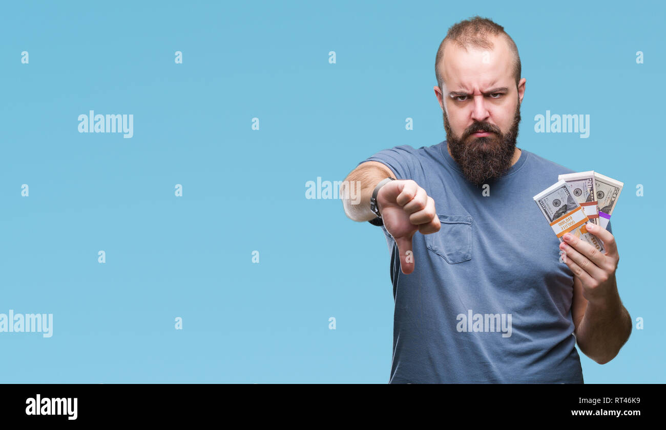 Young hipster man holding bunch of money over isolated background with ...