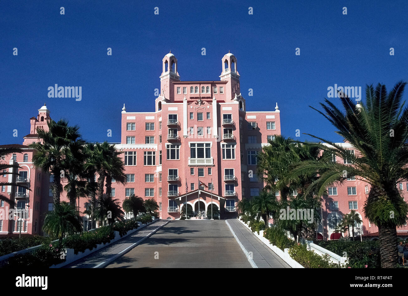 A palm-lined road leads to The Don Cesar, a splendid beach resort and spa that is appropriately called the Pink Palace and sprawls along a sandy shore of the Gulf of Mexico at St. Pete Beach on the west coast of  Florida, USA. Celebrities and other members of high society flocked to the landmark lodging in the Tampa Bay area when it opened in 1928 during the Sunshine State's early boom years. Beginning in 1942 the grand hotel was used as a hospital and convalescent center for wounded World War II soldiers before falling into disrepair. New owners in 1973 restored the towered nine-story hotel. Stock Photo