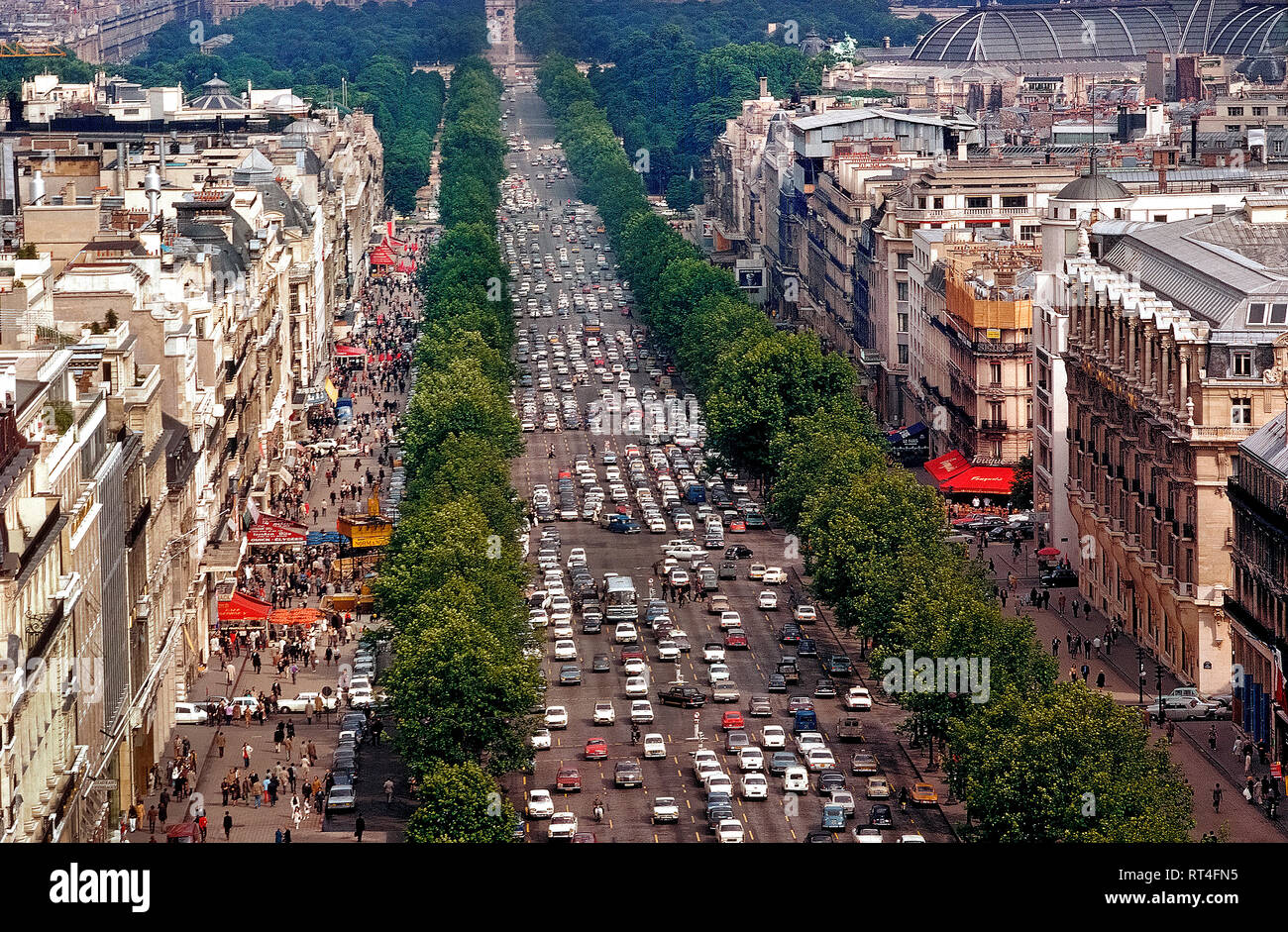 An aerial view shows the beautiful tree-lined Champs-Élysées, one of the busiest and most congested avenues in all of Paris, France. The famous 1.2 mile-long (1.9 km) thoroughfare runs between two of the French capital's monumental landmarks, the Place de la Concorde and Arc de Triomphe. Since this photograph was taken in 1983, the 11 lanes of traffic have been reduced to eight and there are plans to reduce vehicle use even more in order widen the sidewalks and make the street more pedestrian friendly by the mid-2020s. Stock Photo