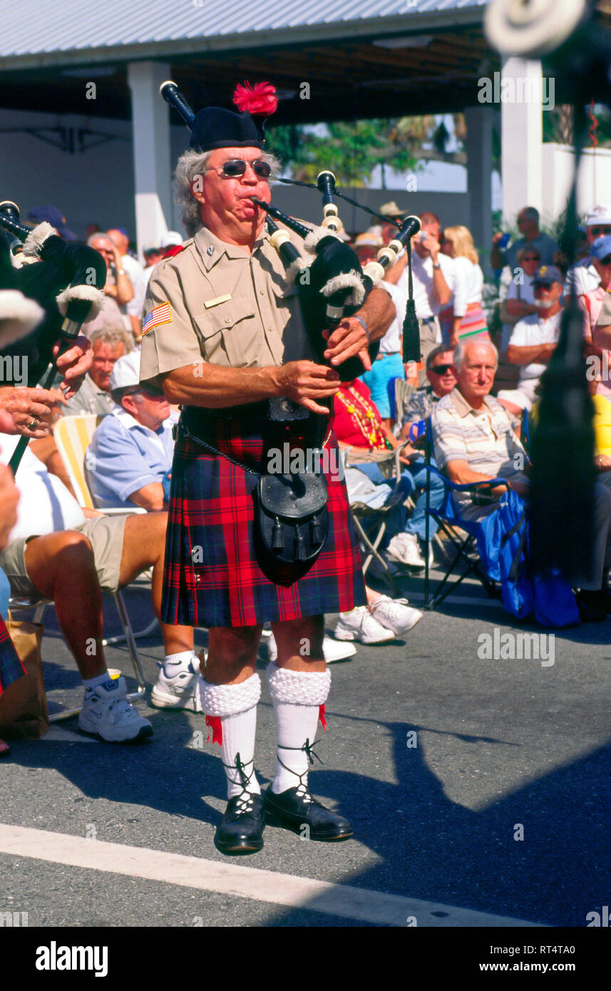 elderly man playing bagpipes; plaid kilt; Scottish dress; cheeks puffy; outdoor festival; ethnic music; audience; entertainment, talent, musician, Flo Stock Photo
