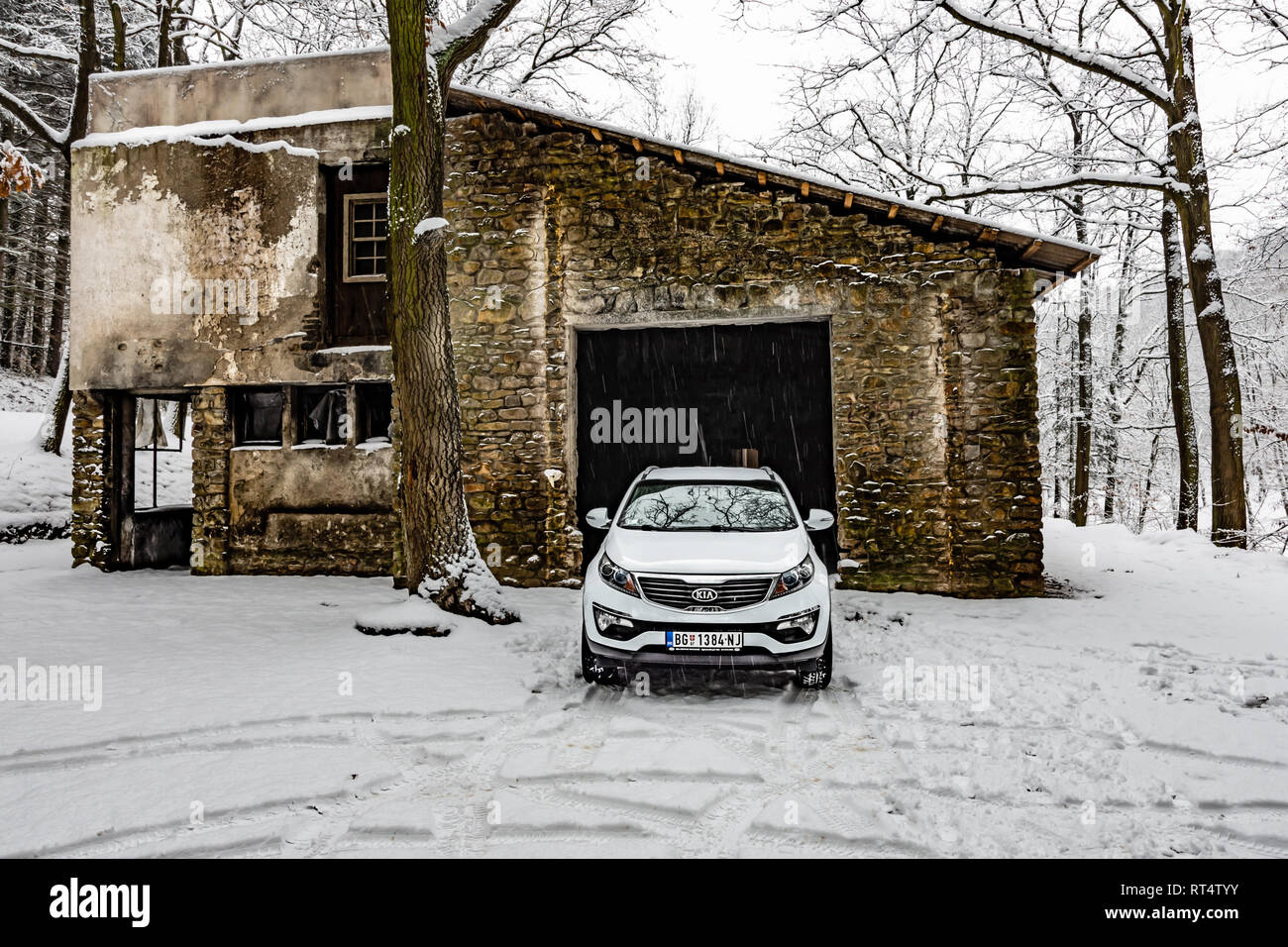 Kia Sportage 2.0 CRDI awd or 4x4, white color, near the abandoned garage in a forest, covered with deep snow and ice. Extreme conditions and temperatu Stock Photo