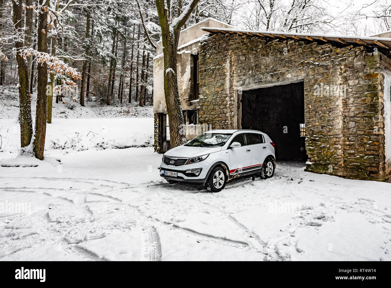 Kia Sportage 2.0 CRDI awd or 4x4, white color, near the abandoned garage in a forest, covered with deep snow and ice. Extreme conditions and temperatu Stock Photo