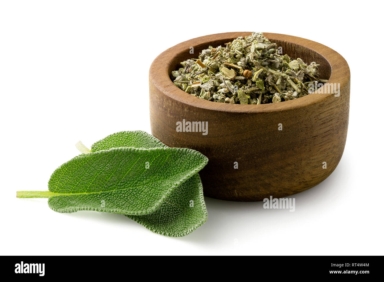 Dried rubbed sage in a dark wood bowl next to fresh sage leaves