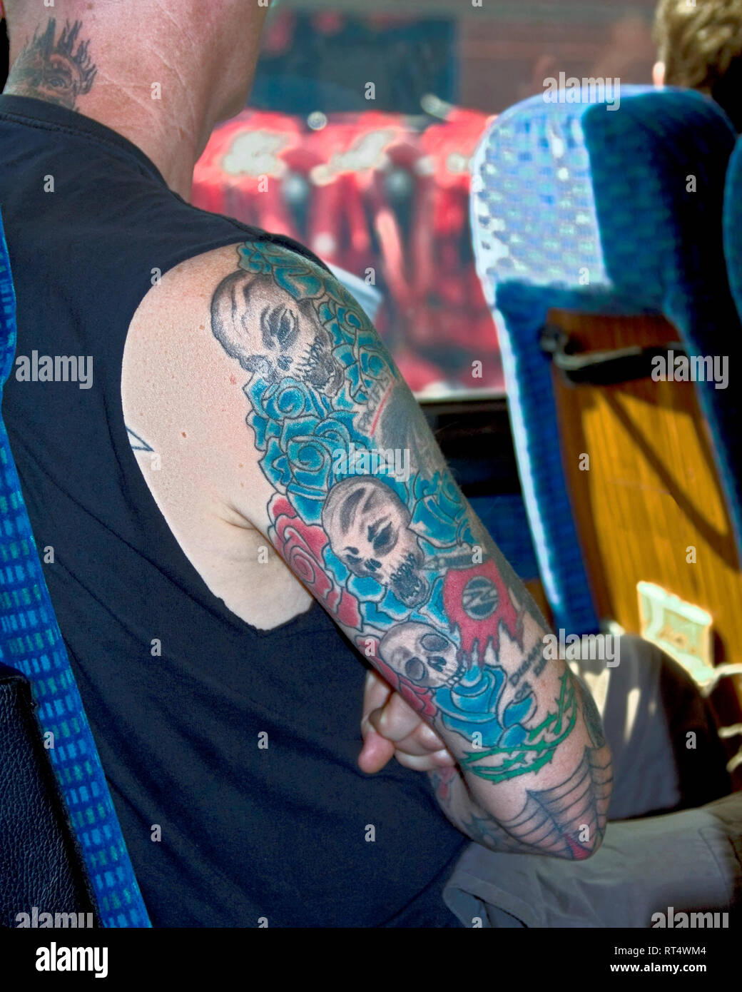 heavily tatooed arm; man; multicolors; Pacifist; Disarm; skin, bus, New Zealand; vertical Stock Photo