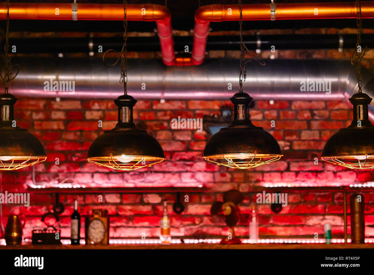 Steampunk style design element unusual lamps hanging in a row view over red brick wall inside cafe or restaurant Stock Photo