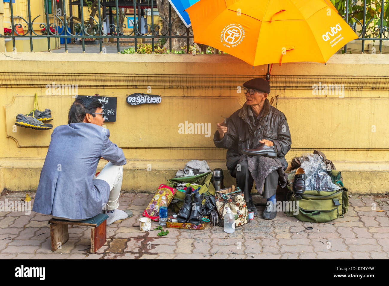 Business man having his shoes cleaned by a street trader in Hanoi Old Quarter, Ha Noi, Vietnam, Asia Stock Photo