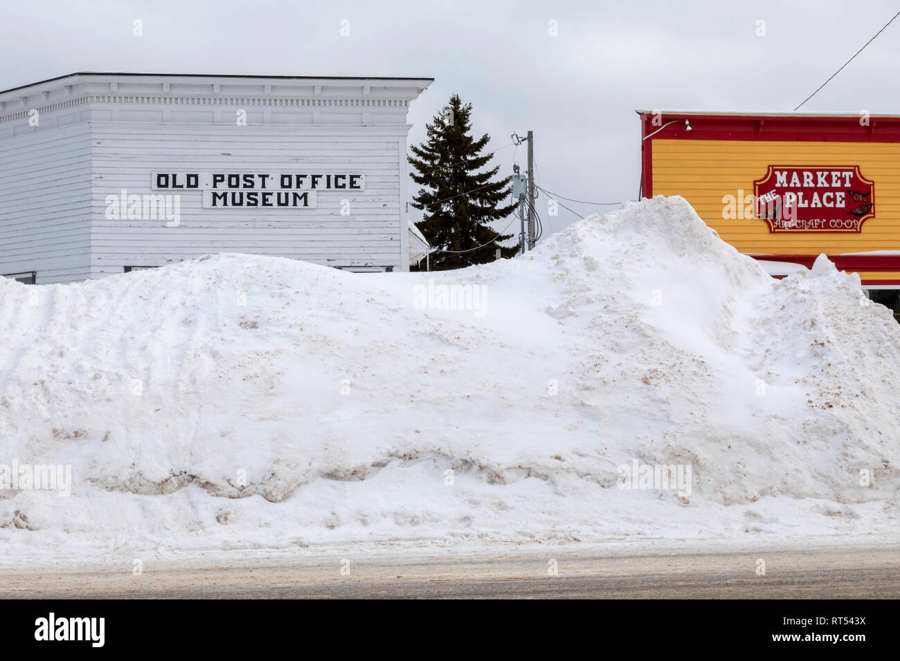 Grand Marais, Michigan - Snow is piled high in front of buildings on the main street. The town, on the shore of Lake Superior, gets an average of 151  Stock Photo