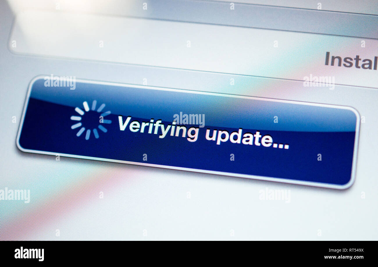 Verifying update message with spinning cursor on a modern tablet screen - tilt shift lens used Stock Photo