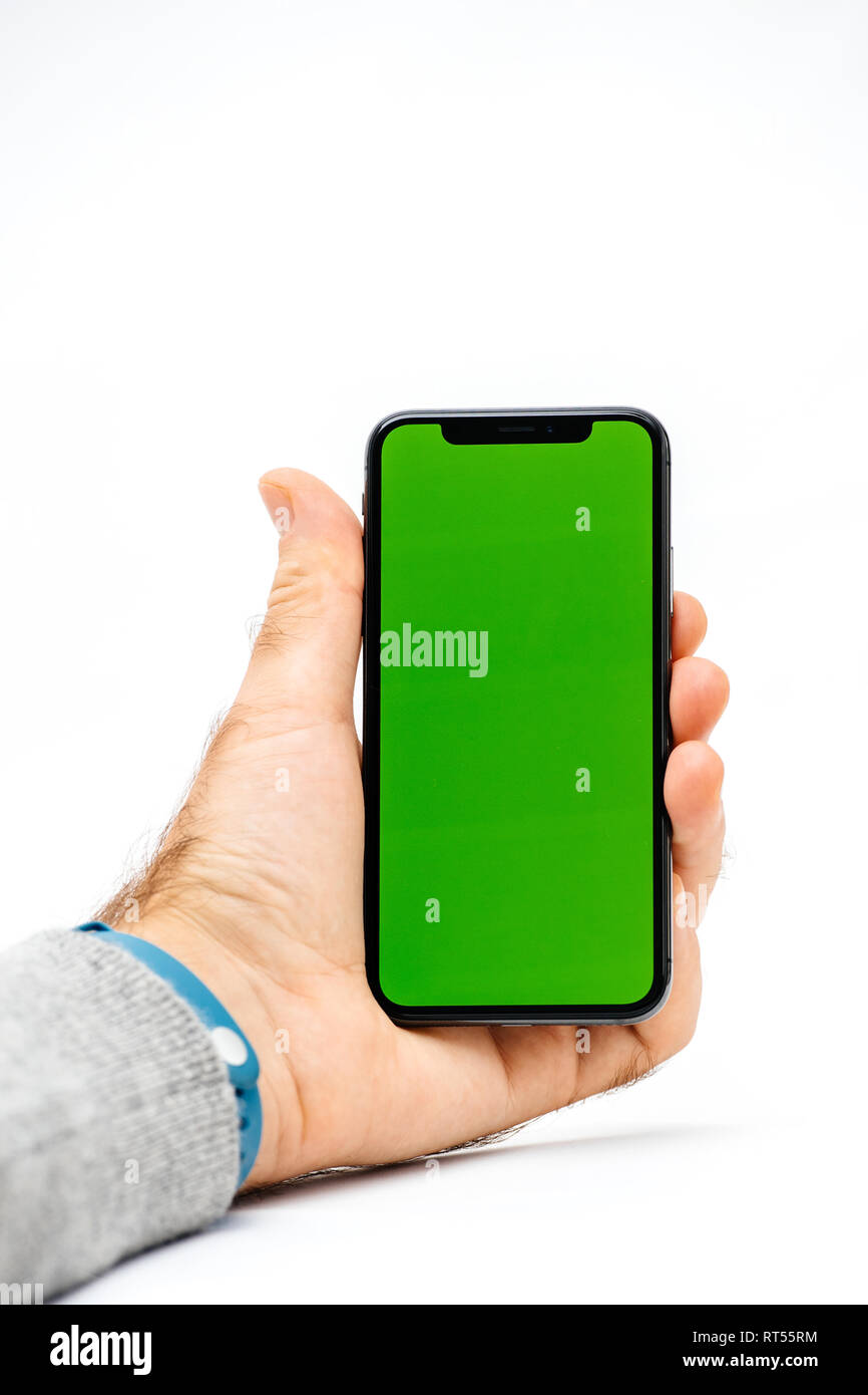 PARIS, FRANCE - NOV 5, 2017: New Apple iPhone X 10 smartphone with green chroma key backdrop against white background in male hand Stock Photo