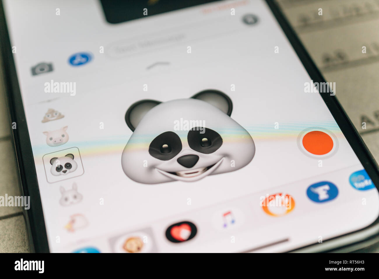 PARIS, FRANCE - NOV 9 2017: Panda bear 3d animoji emoji generated by Face ID facial recognition system with large smile face emotion close-up of the new iphone X 10 Display - tilt-shift lens used  Stock Photo