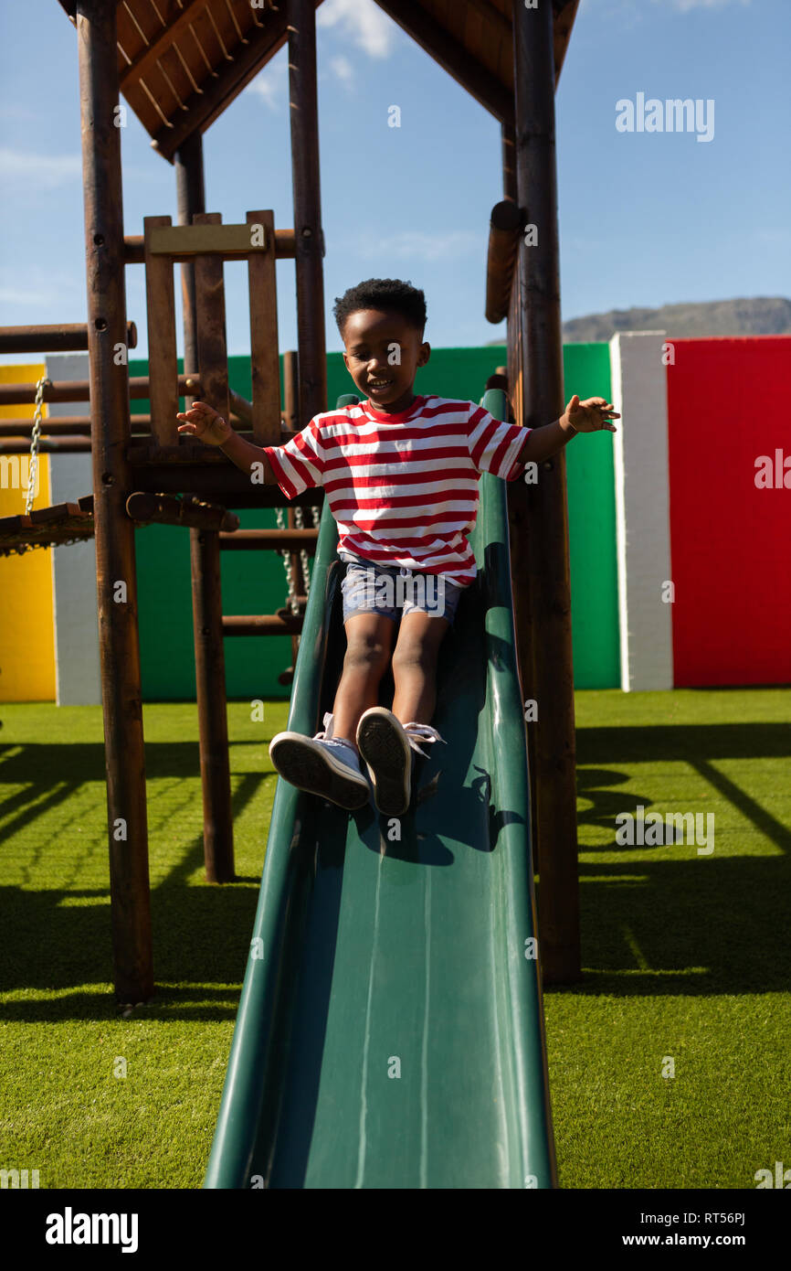 Schoolboy playing on a slide at school playground Stock Photo