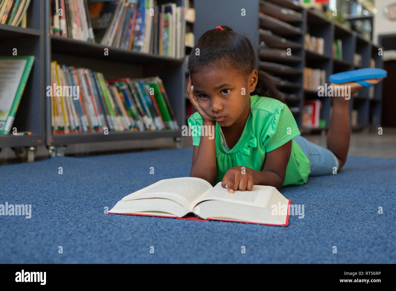 Schoolgirl reading a book in the library Stock Photo - Alamy