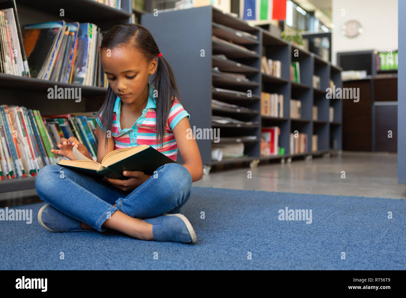 Schoolgirl reading a book in the library Stock Photo - Alamy