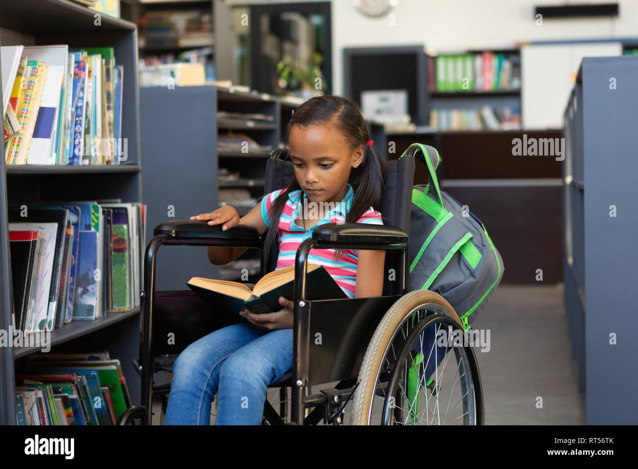 Disabled schoolgirl reading a book in the library Stock Photo - Alamy