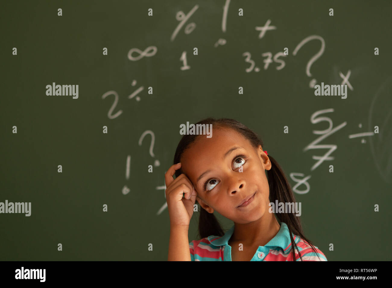 Schoolgirl standing against green board in a classroom at school Stock ...