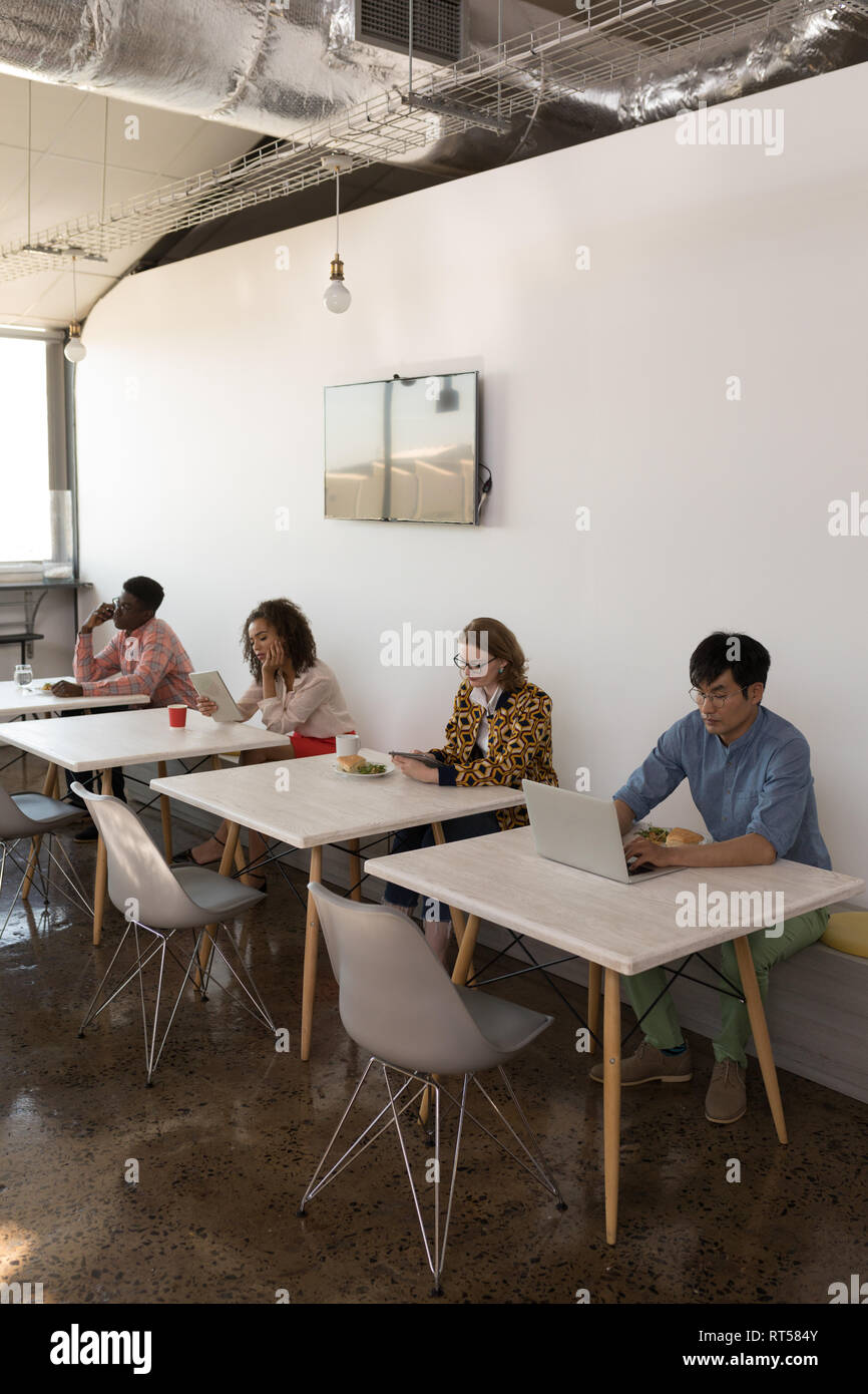 Business colleagues using multimedia devices in canteen Stock Photo