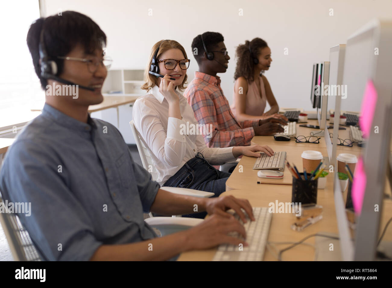 Executives working on personal computer while talking on headset in office Stock Photo