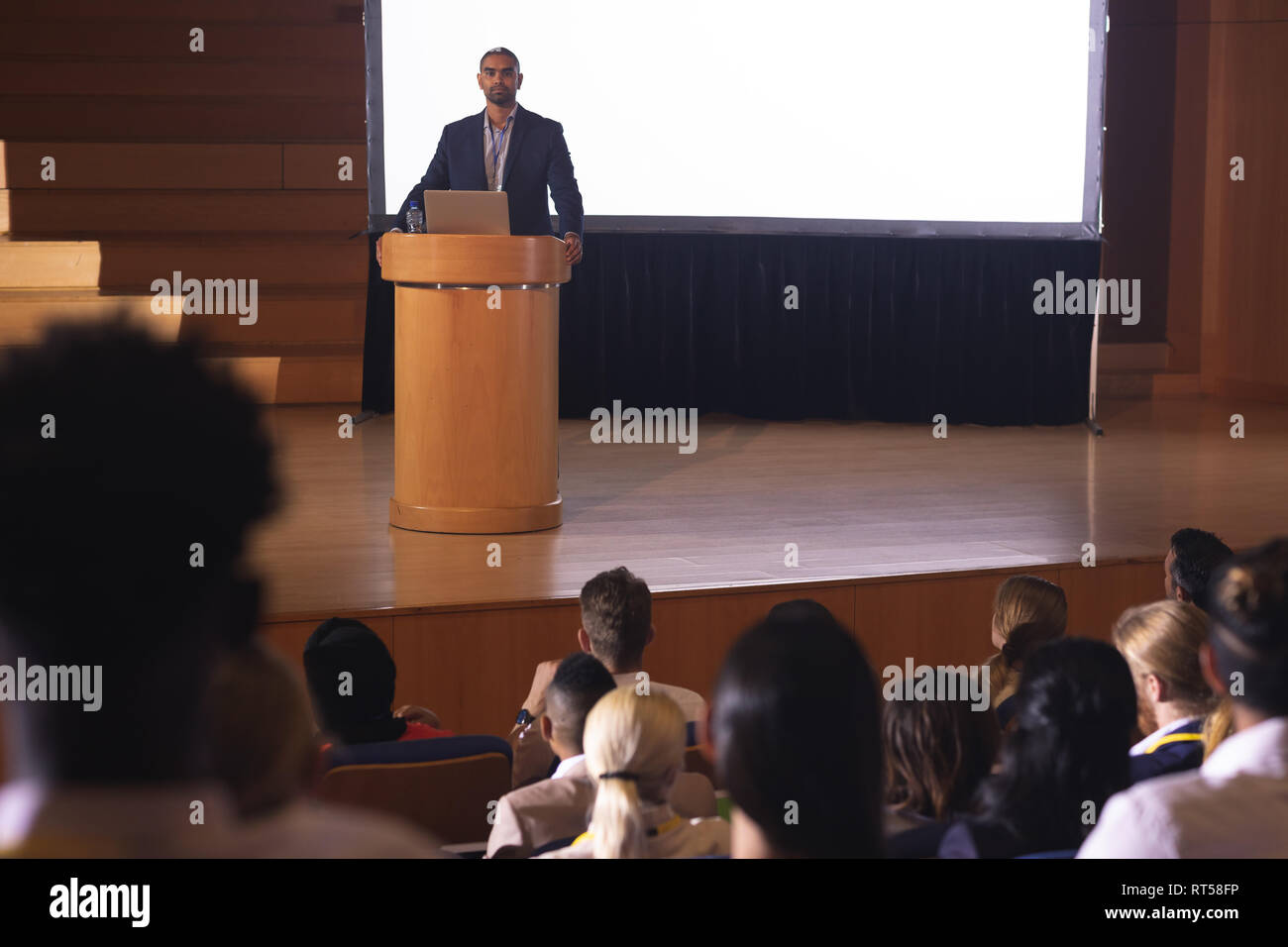 Businessman standing around the podium and giving speech in front of