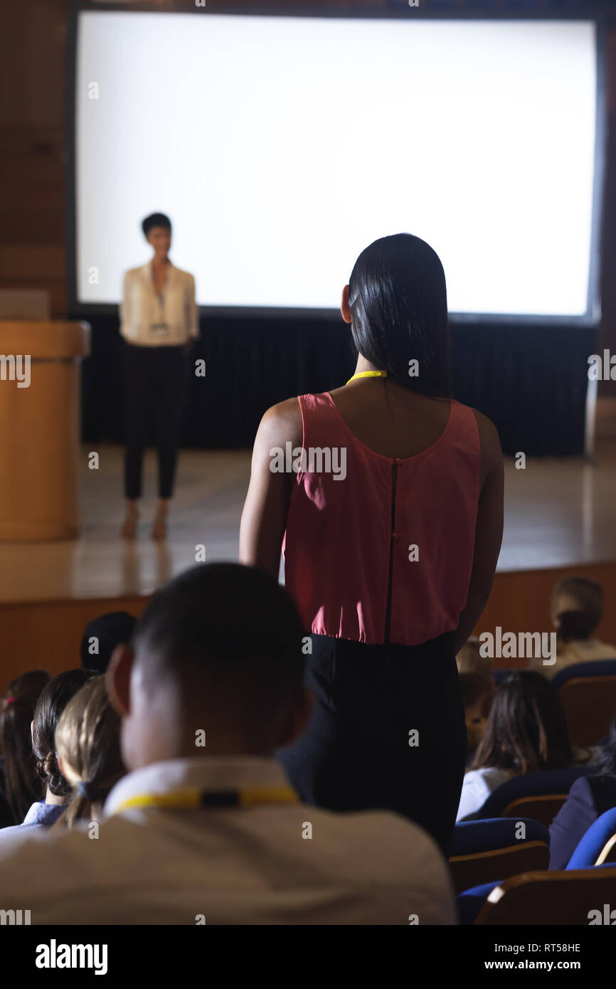 Woman from the audience standing and asking query in the auditorium Stock Photo