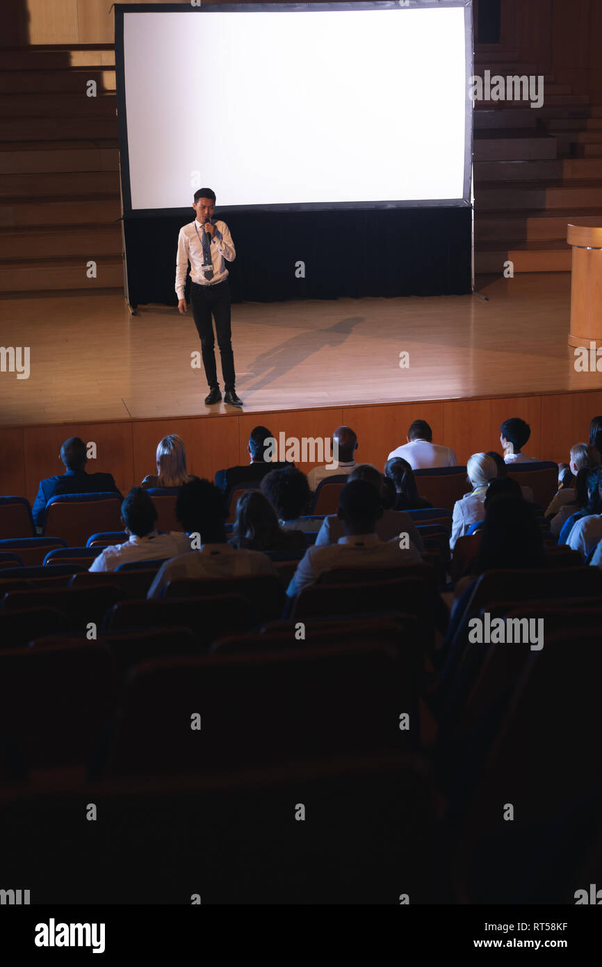 Businessman standing and giving presentation in auditorium Stock Photo