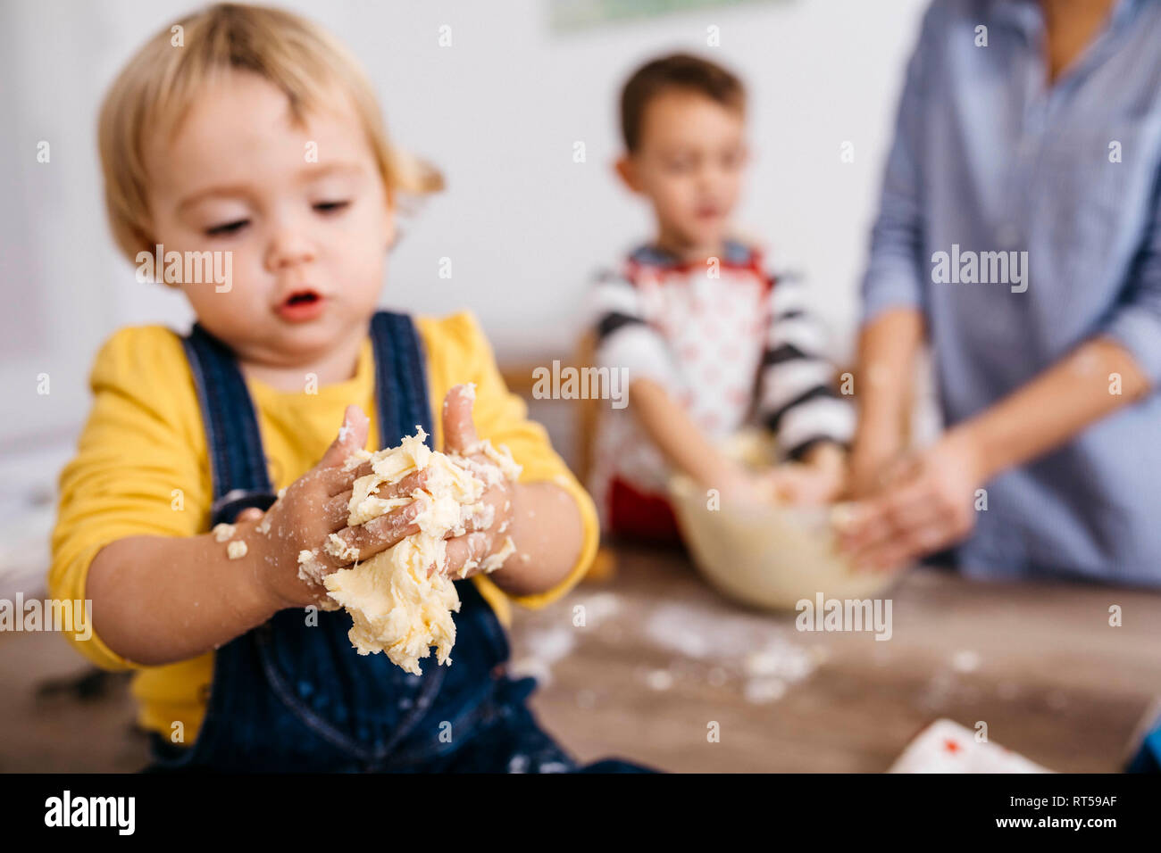 Toddler girl kneading dough with hers hands, close-up Stock Photo
