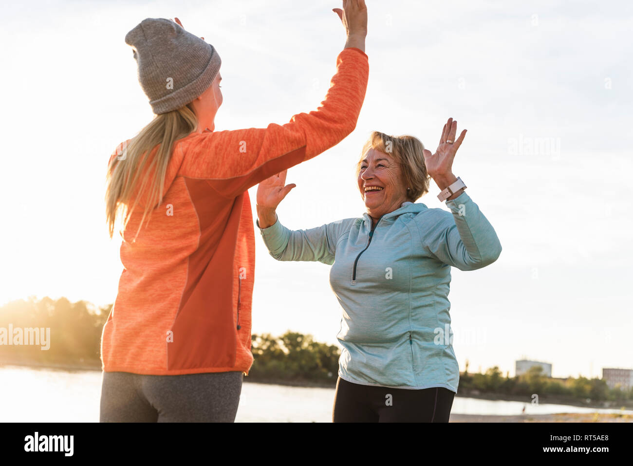 Grandmother and granddaughter high-fiving after training at the river Stock Photo