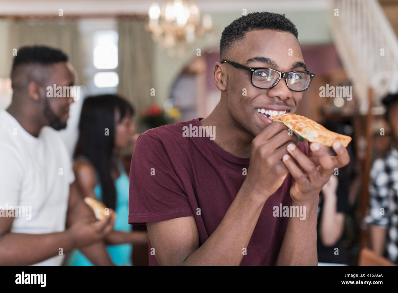 Portrait smiling teenage boy eating pizza with family Stock Photo