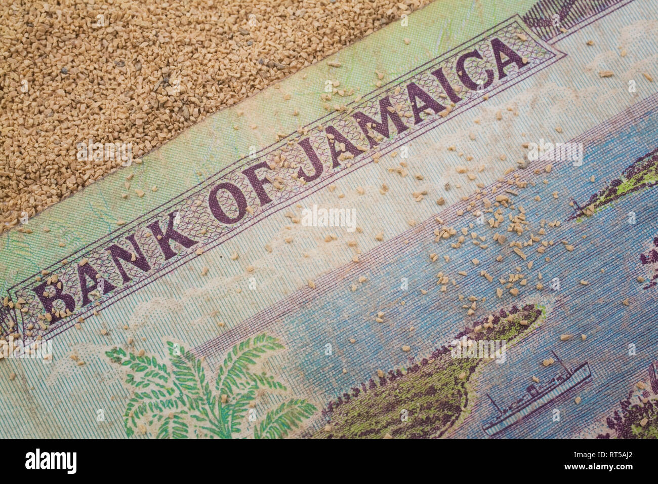 Close-up of a Bank of Jamaica paper currency banknote on a tan coarse-grained sand background Stock Photo