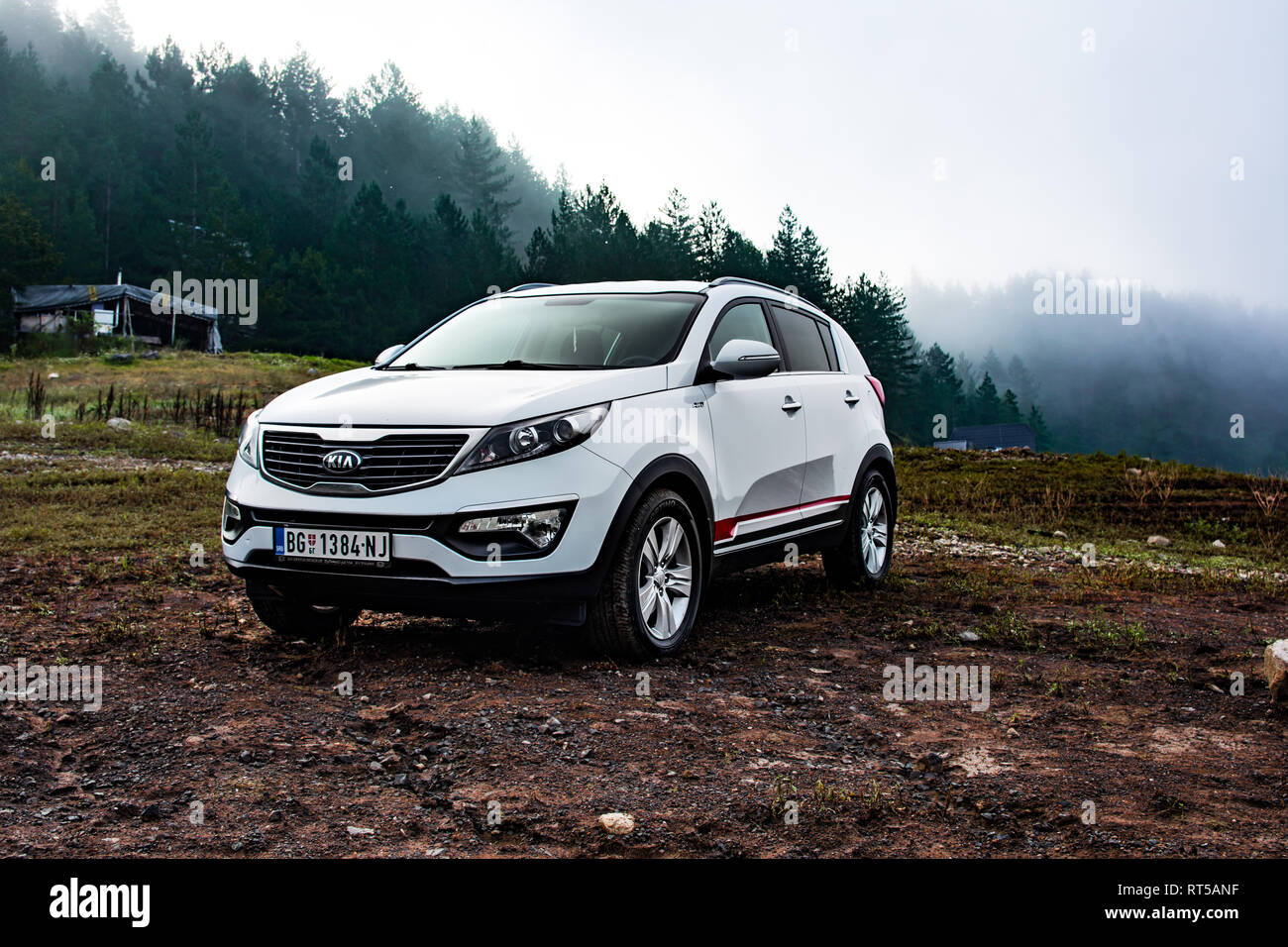 Kia Sportage 2.0 CRDI awd or 4x4, parked in a mudy coast of a lake Zaovine on Mount Tara. With a beautiful forest, and water vapor in the backgorund. Stock Photo