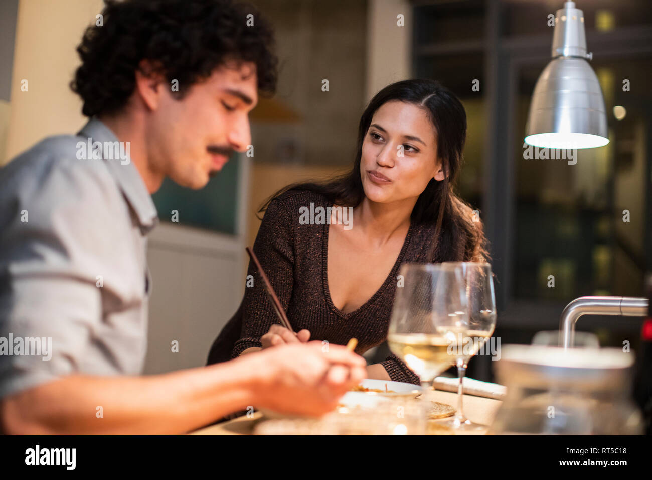Couple eating dinner with chopsticks and drinking white wine at home Stock Photo