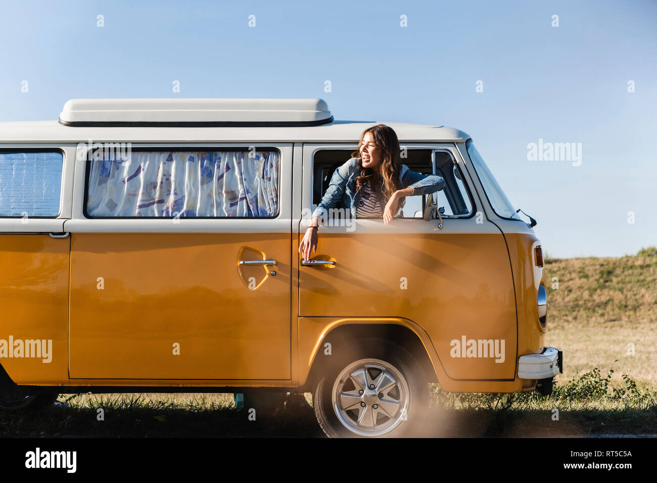 Pretty woman on a road trip with her camper, looking out of car window ...