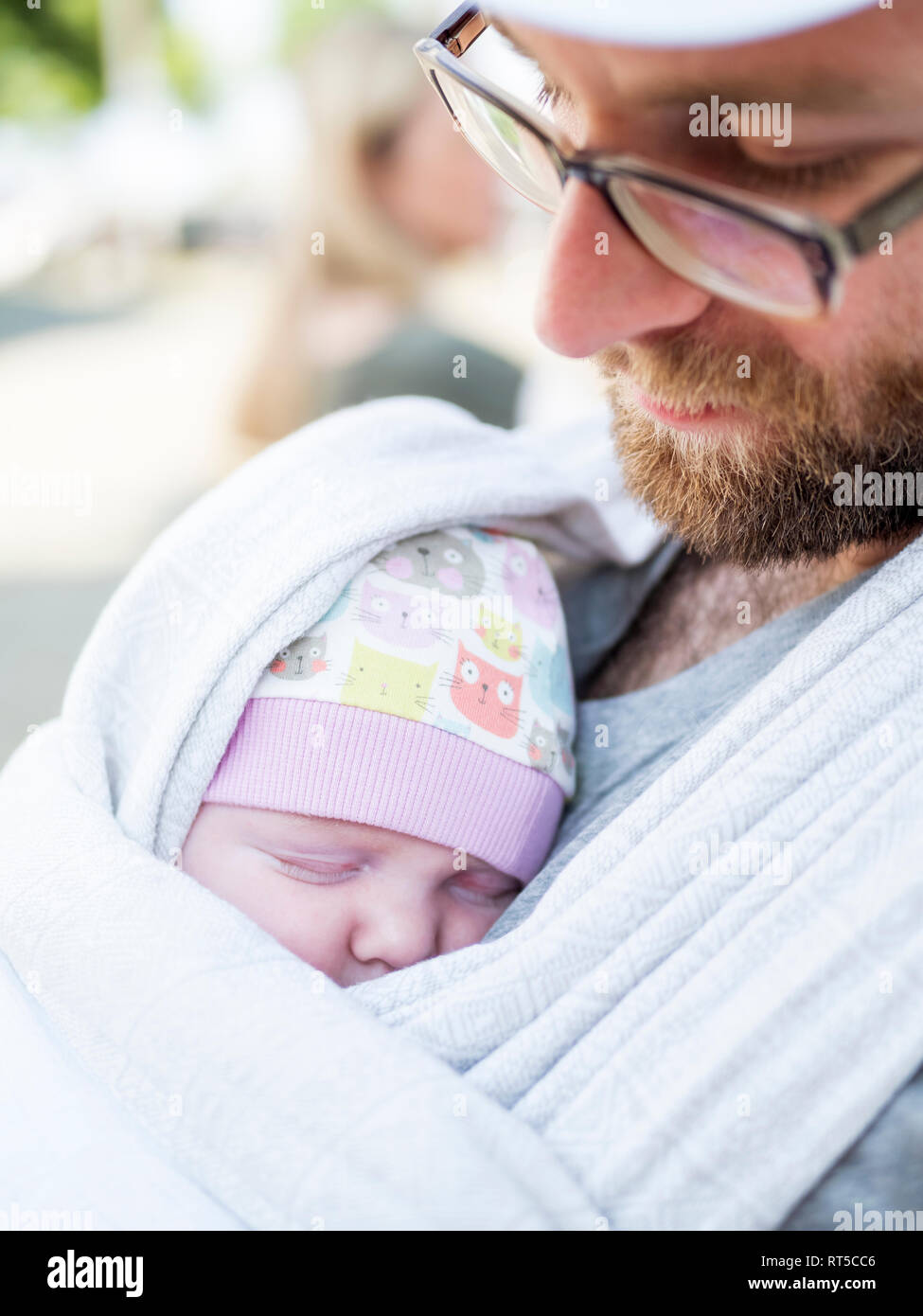 Father carrying his baby daughter on his chest in  a sling Stock Photo