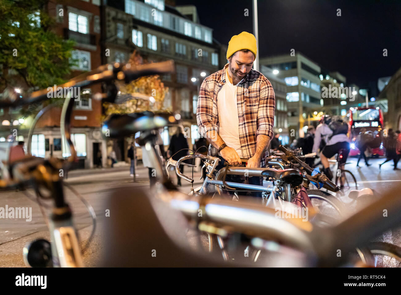 UK, London, man unlocking his bike and commuting at night in the city Stock Photo