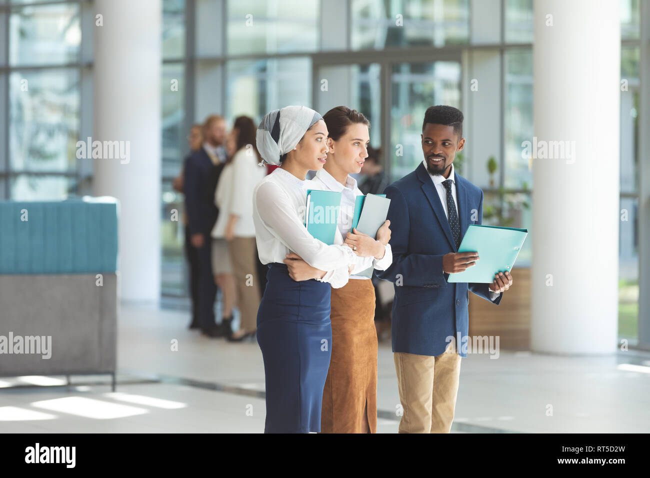 Business executives standing with files in lobby office Stock Photo - Alamy